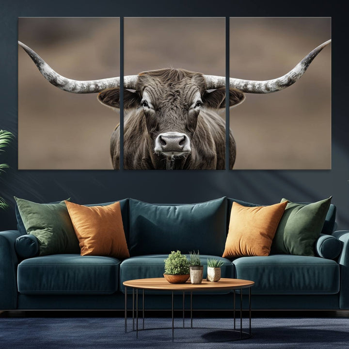 A close-up of a longhorn bull facing forward is featured in the Framed Texas Test-1, set against a blurred brown background.