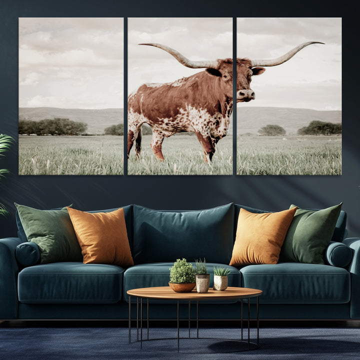 Canvas of a Texas longhorn standing in a grassy field with mountains in the background, ideal for rustic or country-style western wall decor.