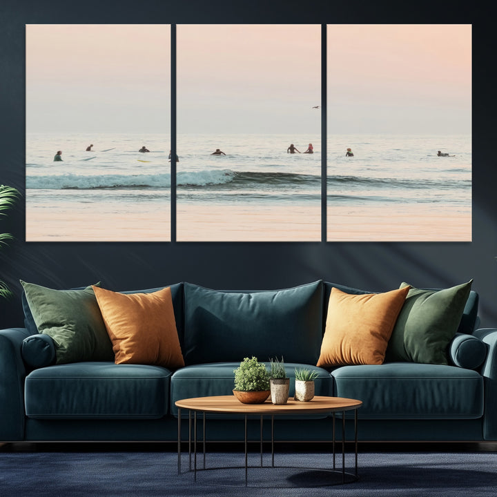 Dreamy photo of surfers waiting on soft pastel waves under a pink sunset sky, ideal for soft coastal minimalist or serene ocean-themed home decor.