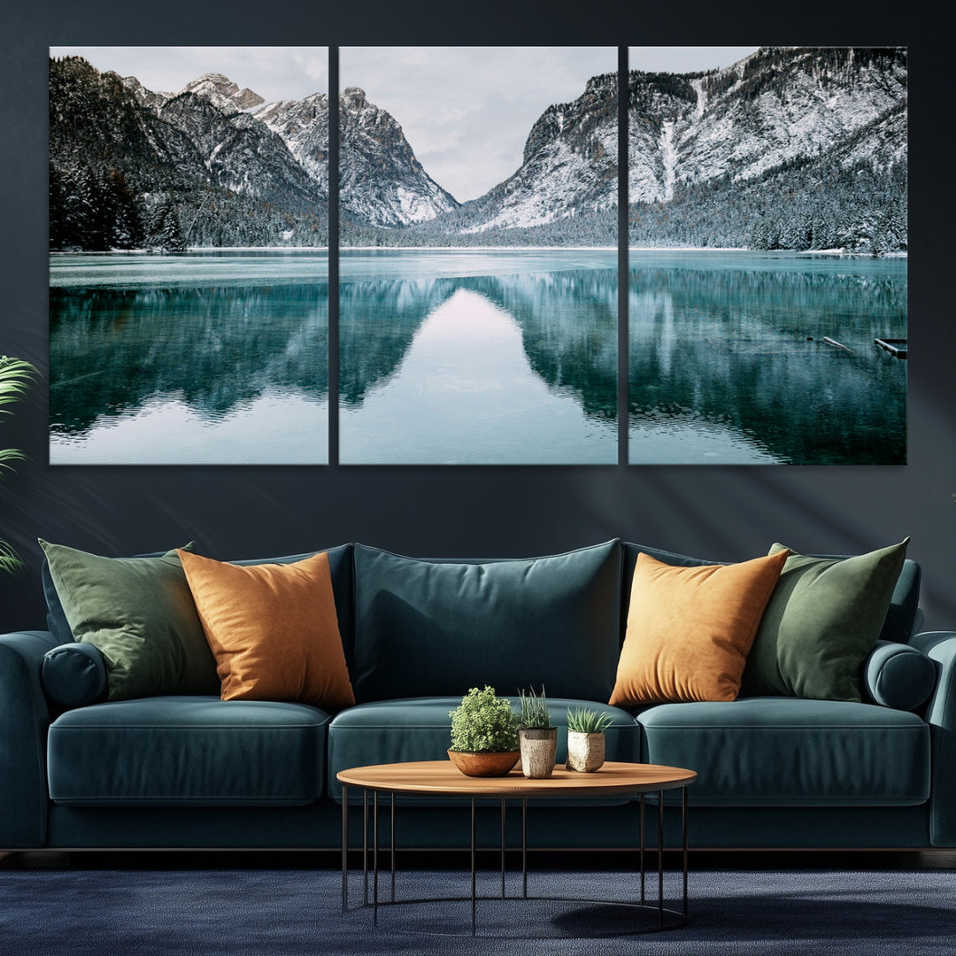 Crystal-clear alpine lake reflecting snow-covered mountains, surrounded by evergreen trees, creating a serene and tranquil winter landscape.
