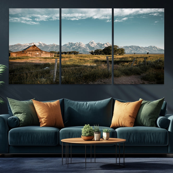 A rustic farmhouse with a wooden barn set against majestic mountain peaks under a soft blue sky, evoking peaceful countryside charm.