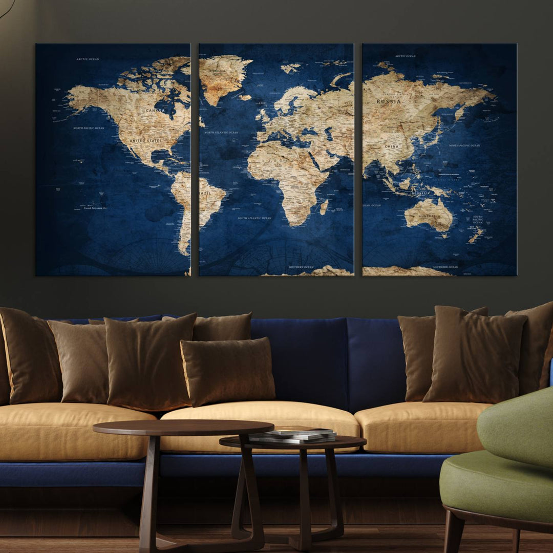 A large framed world map canvas print features beige landmasses set against a grunge-stained deep blue ocean background, creating an intriguing piece of wall art.