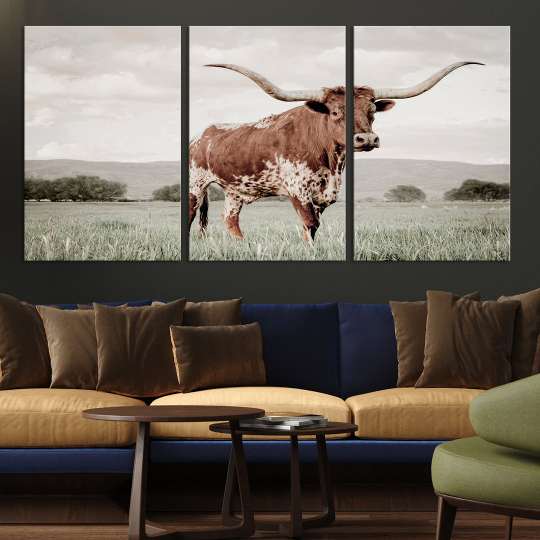 Canvas of a Texas longhorn standing in a grassy field with mountains in the background, ideal for rustic or country-style western wall decor.