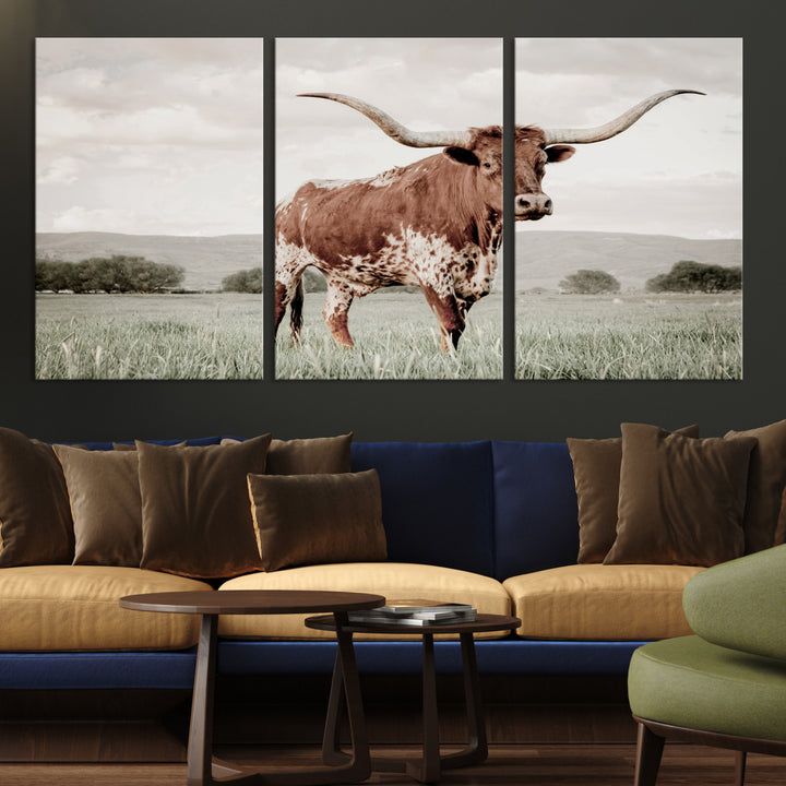 Canvas of a Texas longhorn standing in a grassy field with mountains in the background, ideal for rustic or country-style western wall decor.