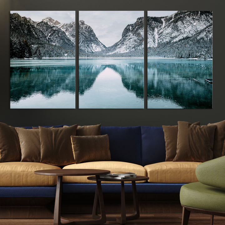 Crystal-clear alpine lake reflecting snow-covered mountains, surrounded by evergreen trees, creating a serene and tranquil winter landscape.