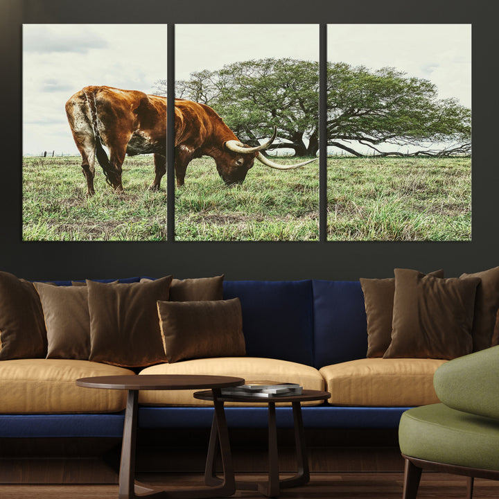 A Texas Longhorn grazing in a green pasture with a large tree in the background, evoking a rustic Western and farmhouse aesthetic.