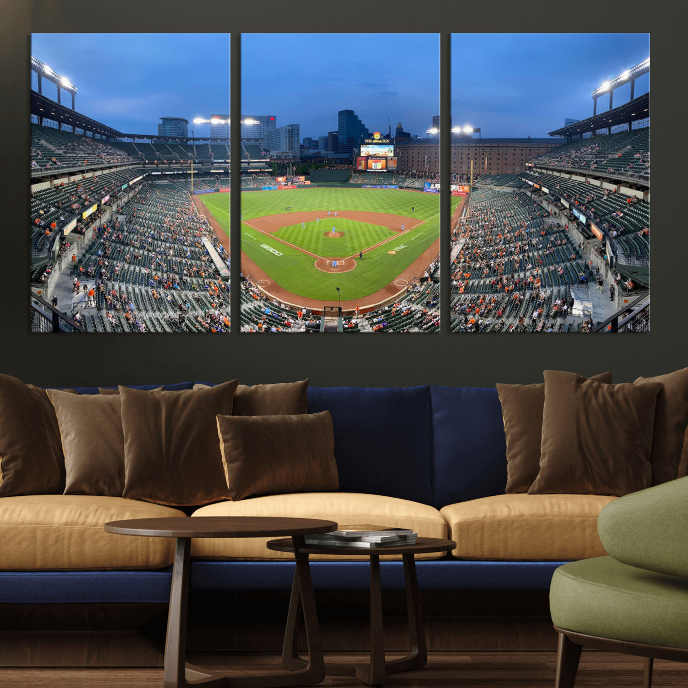 Wide panoramic view of a baseball stadium at dusk with players on the field, stadium lights illuminating the scene, and a sparse crowd of spectators in the stands.