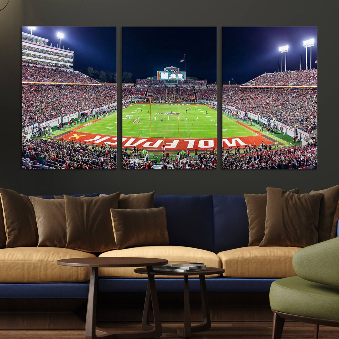 A NC State Wolfpack Football Team print of Carter-Finley Stadium at night features WOLFPACK illuminated brightly in the end zone grass.