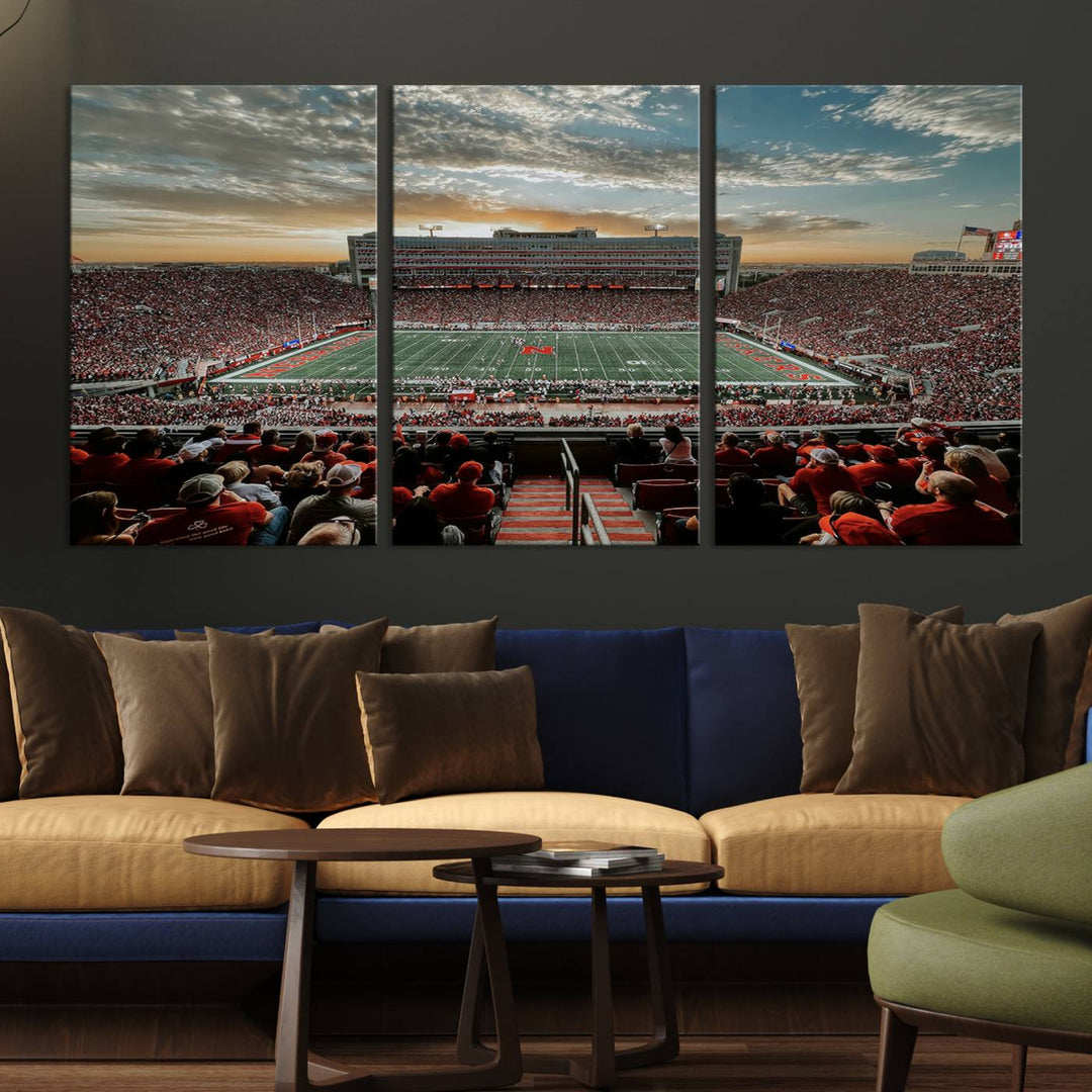 The living room features a stunning triptych of Lincoln Memorial Stadium wall art canvas print, celebrating the University of Nebraska Cornhuskers football team. This piece serves as captivating wall art, showcasing a gallery-quality finish.