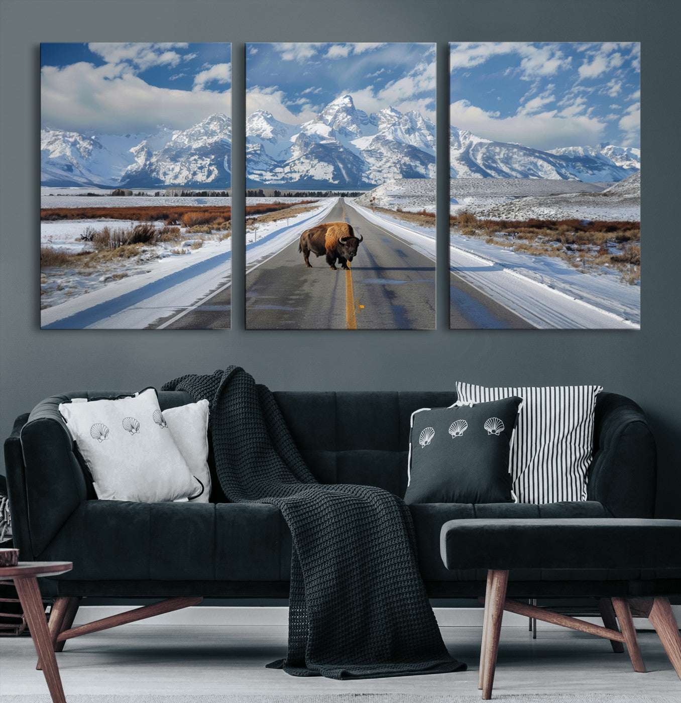 A powerful bison stands on a snow-dusted road beneath the towering peaks of the Grand Tetons, capturing the untamed beauty of America's winter wilderness.