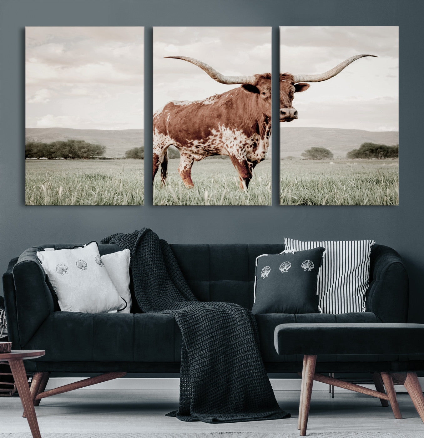 Canvas of a Texas longhorn standing in a grassy field with mountains in the background, ideal for rustic or country-style western wall decor.