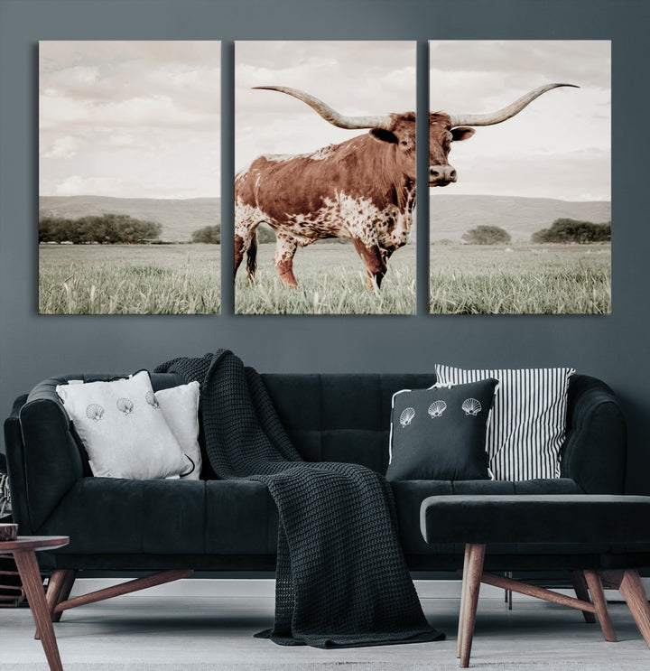 Canvas of a Texas longhorn standing in a grassy field with mountains in the background, ideal for rustic or country-style western wall decor.