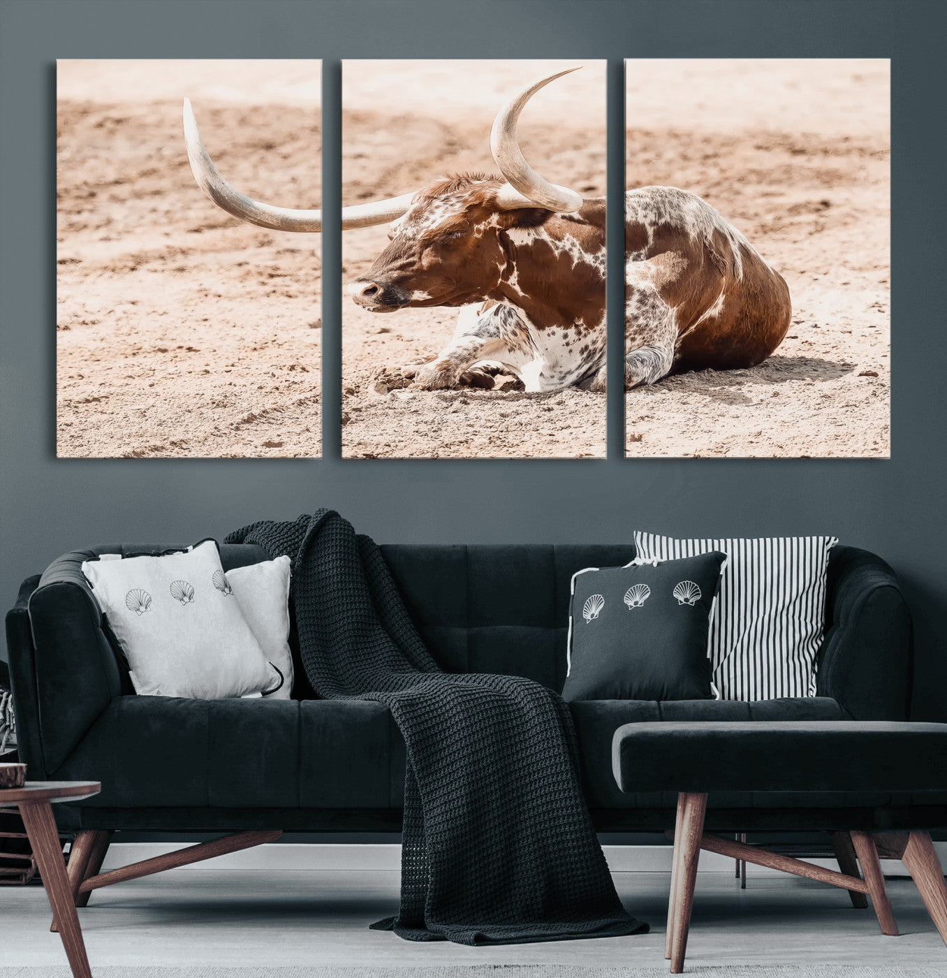 Texas Longhorn bull resting on dusty ground with warm tones, ideal for rustic western or farmhouse-themed wall decor.
