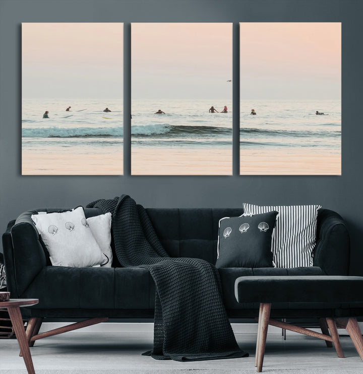 Dreamy photo of surfers waiting on soft pastel waves under a pink sunset sky, ideal for soft coastal minimalist or serene ocean-themed home decor.