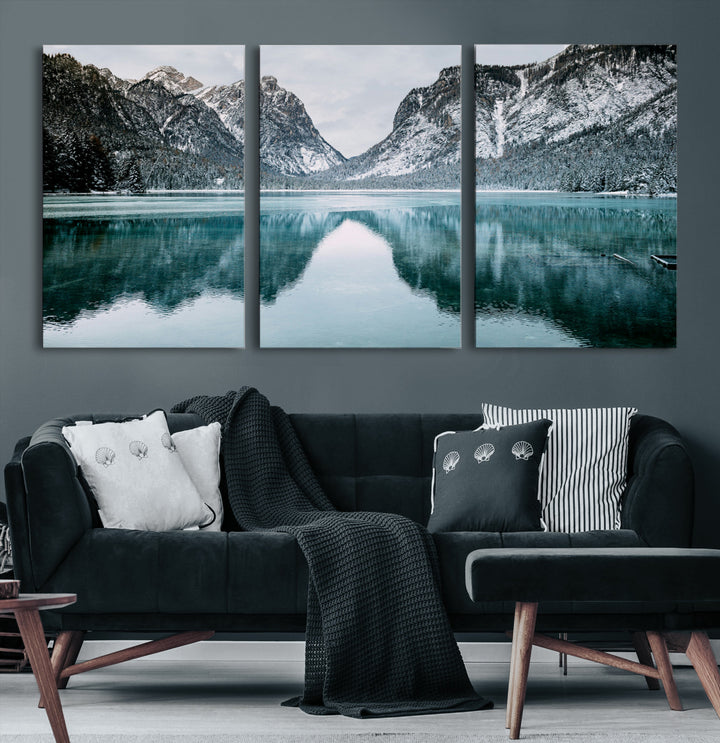 Crystal-clear alpine lake reflecting snow-covered mountains, surrounded by evergreen trees, creating a serene and tranquil winter landscape.