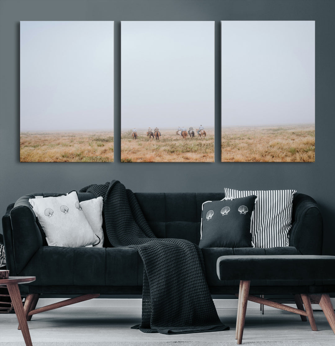 A group of horseback riders moving through a fog-shrouded field, evoking a calm Western scene with golden grasses and soft horizons.