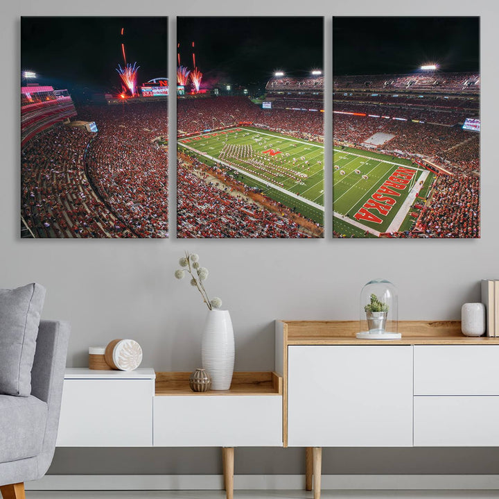 The University of Nebraska Cornhuskers Football Team Print, featuring Lincoln Memorial Stadium in a vibrant triptych canvas with fireworks above and a gallery-quality finish, is elegantly displayed.