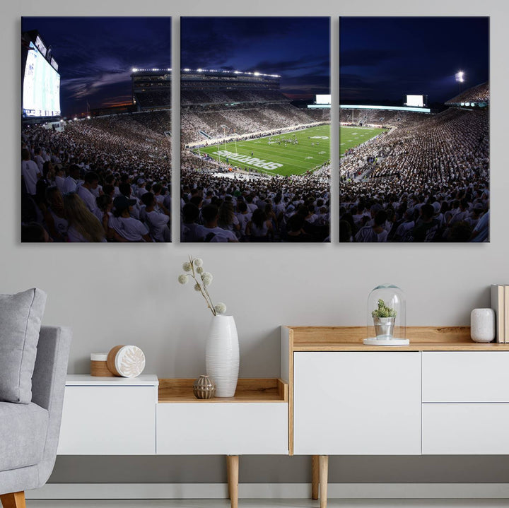 A packed football stadium at night, with bright lights and fans in white, depicted in a Michigan State Spartans Stadium wall art.