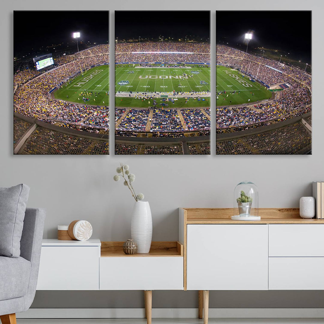 A large football stadium at night, featuring the UCONN Huskies, is depicted on the East Hartford Pratt & Whitney Stadium Wall Art Canvas Print.