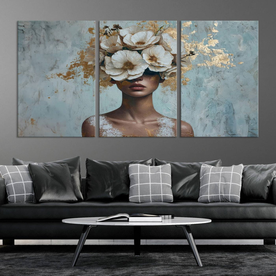 The Golden Petal Silhouette Woman Wall Art Canvas Print, a large 3-panel canvas with a textured gold floral design, serves as a luxurious centerpiece in modern glam settings. The artwork depicts a woman with flowers over her eyes against a textured background and hangs elegantly.