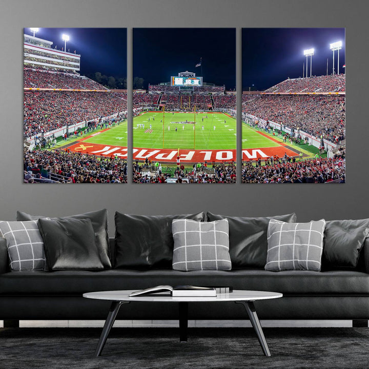 A NC State Wolfpack Football Team print of Carter-Finley Stadium at night features WOLFPACK illuminated brightly in the end zone grass.