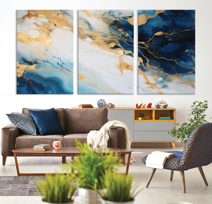 A modern living room featuring museum-quality Blue Gold Abstract Wall Art Print Contemporary art in a triptych arrangement.