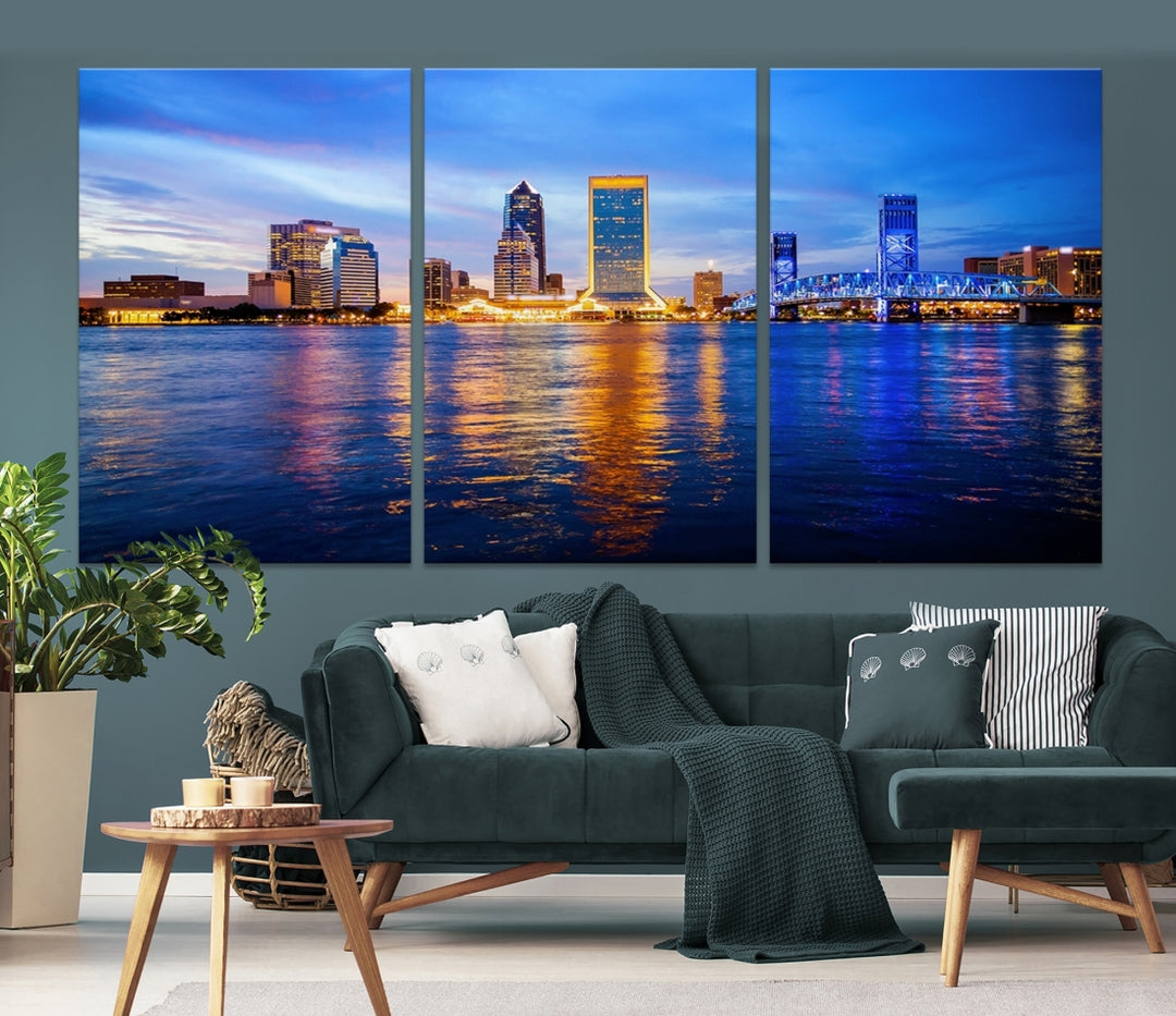 A cozy living room features the Jacksonville Wall Art Canvas Print, a large triptych crafted on museum-quality canvas that beautifully depicts the Jacksonville city skyline at sunset.