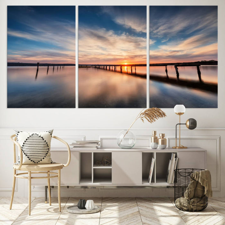 The tranquil sunset casting its glow over a peaceful lake with a long wooden pier captures the essence of coastal allure. The soft clouds mirrored in the water beautifully evoke the ambiance provided by the Sunset Pier Giclee Canvas Wall Art, a masterpiece designed for modern home decor and reminiscent of minimalist art.