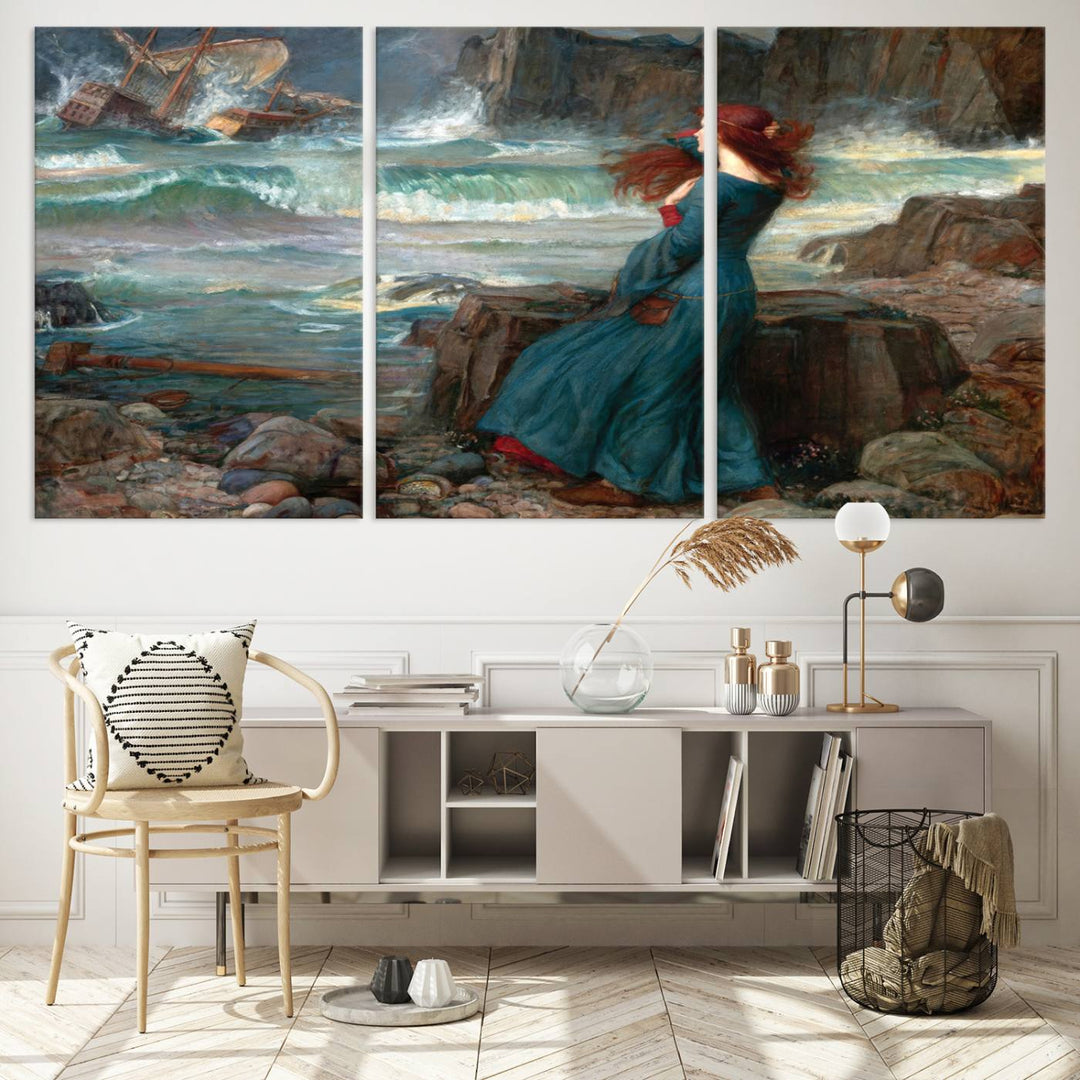 Miranda - The Tempest Canvas Print depicts a woman in a blue dress gazing at a shipwreck on a rocky shore. The artwork is ready to hang.