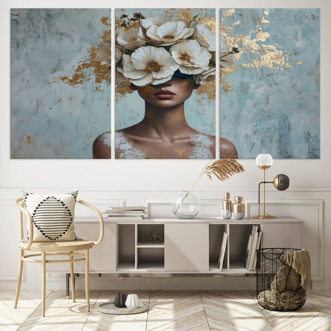 The Golden Petal Silhouette Woman Wall Art Canvas Print, a large 3-panel canvas with a textured gold floral design, serves as a luxurious centerpiece in modern glam settings. The artwork depicts a woman with flowers over her eyes against a textured background and hangs elegantly.