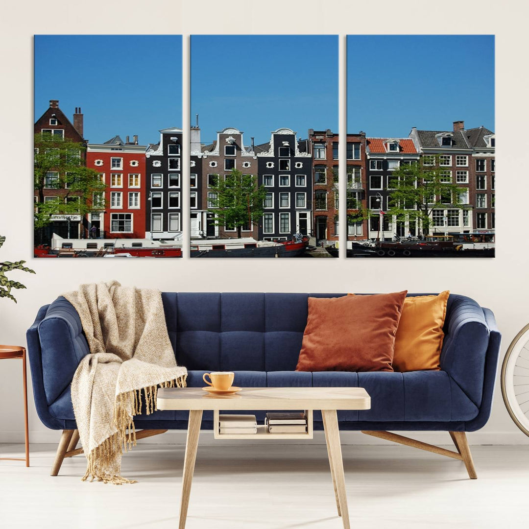 The Amsterdam City Wall Art Canvas Print showcases colorful traditional canal houses and boats set against a clear blue sky.