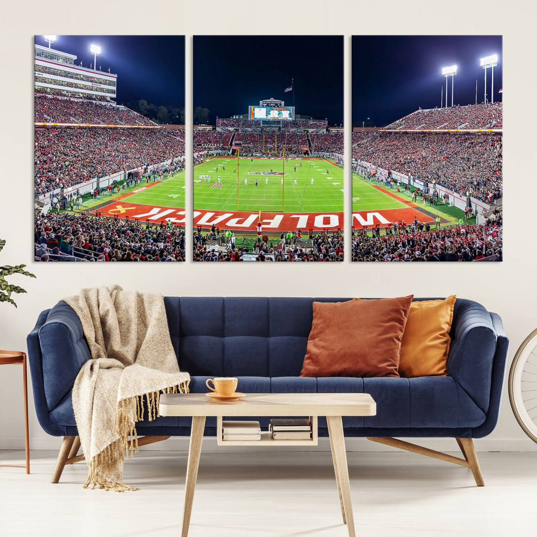 A NC State Wolfpack Football Team print of Carter-Finley Stadium at night features WOLFPACK illuminated brightly in the end zone grass.