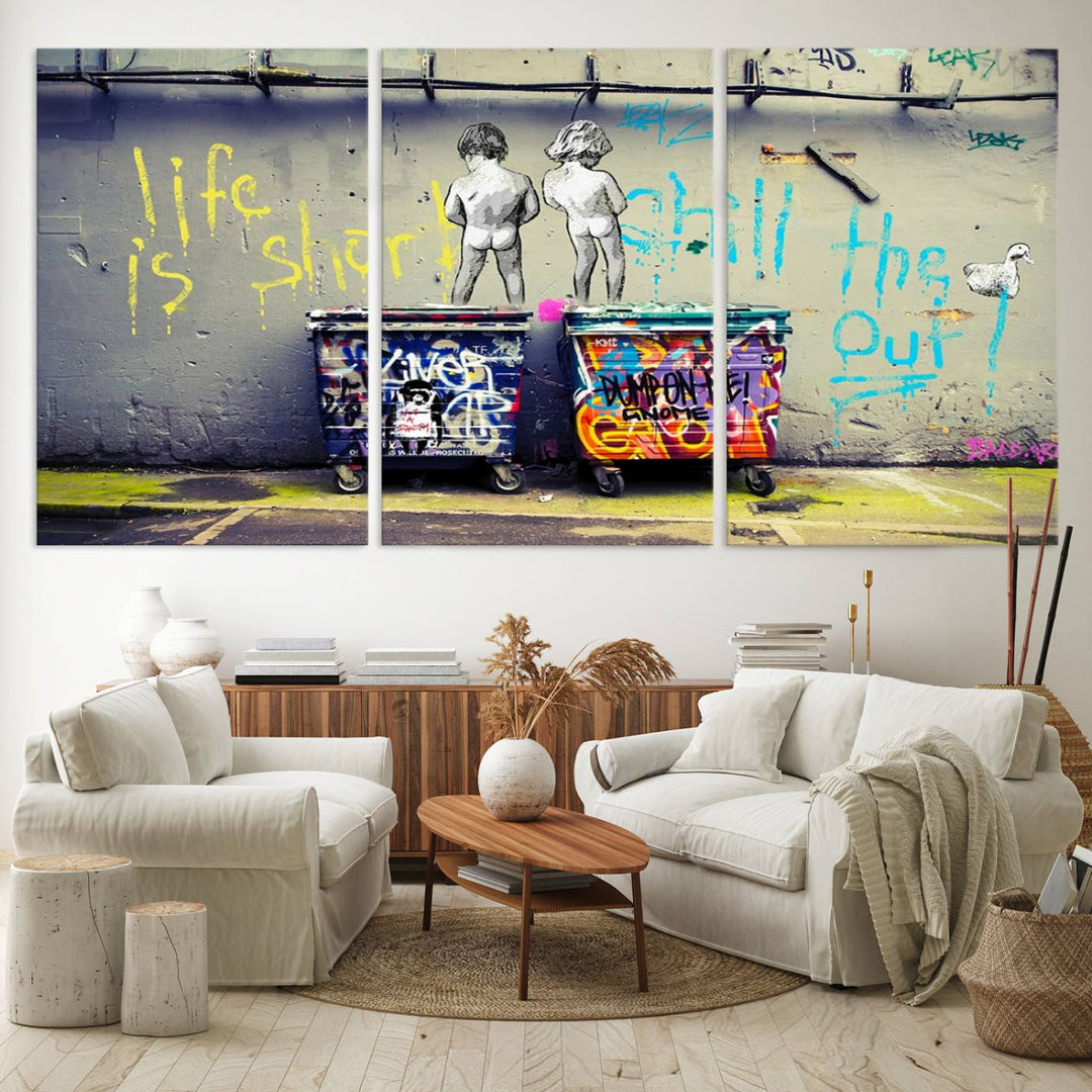 Banksys Life is Short graffiti, featuring kids and text, decorates the wall as a striking piece of framed canvas art.