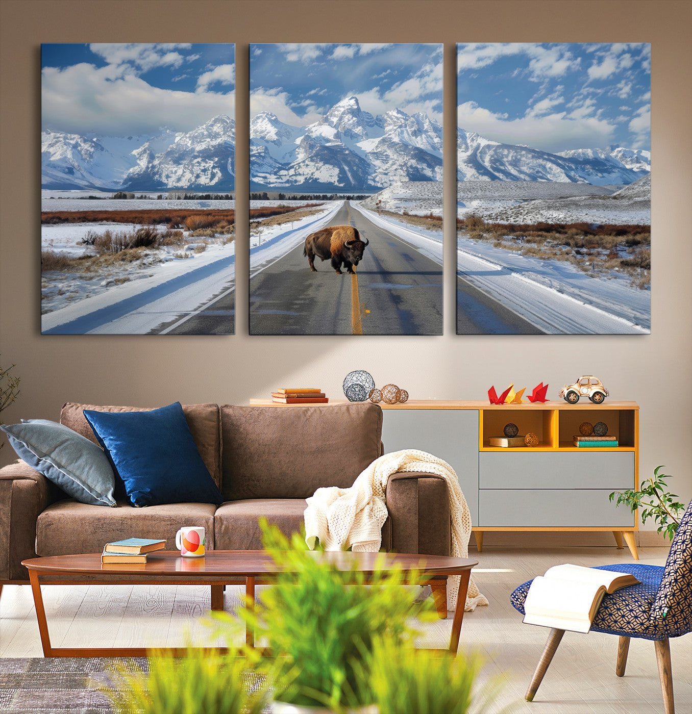 A powerful bison stands on a snow-dusted road beneath the towering peaks of the Grand Tetons, capturing the untamed beauty of America's winter wilderness.