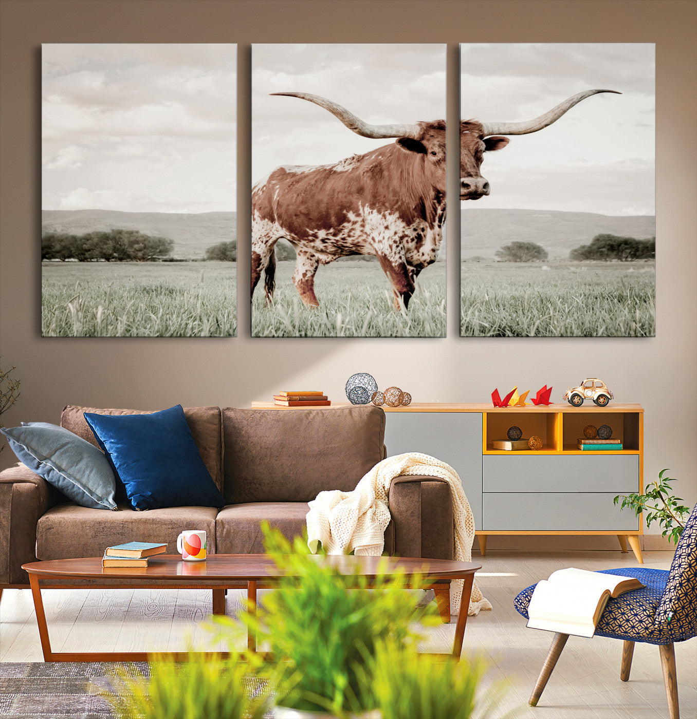 Canvas of a Texas longhorn standing in a grassy field with mountains in the background, ideal for rustic or country-style western wall decor.