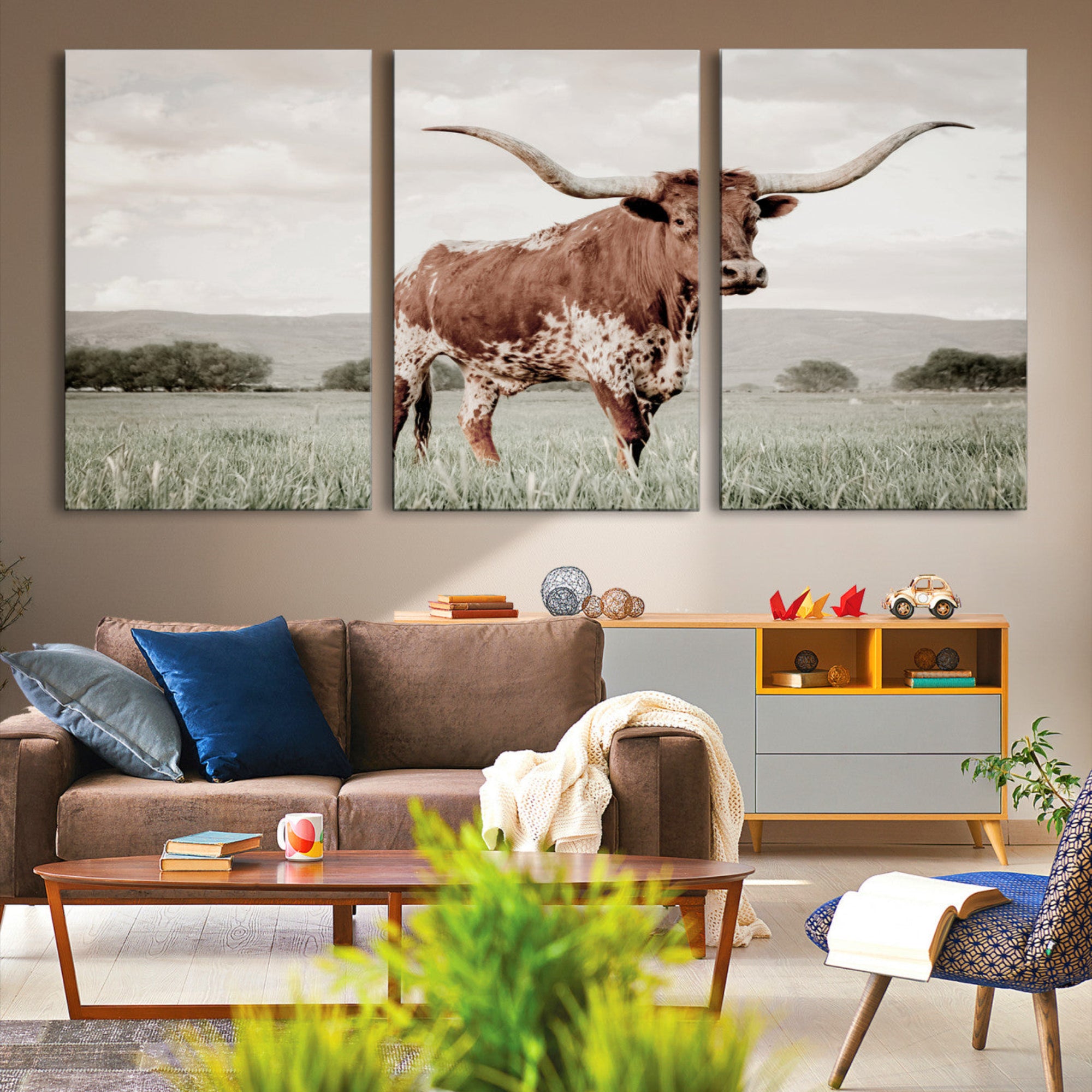 Canvas of a Texas longhorn standing in a grassy field with mountains in the background, ideal for rustic or country-style western wall decor.