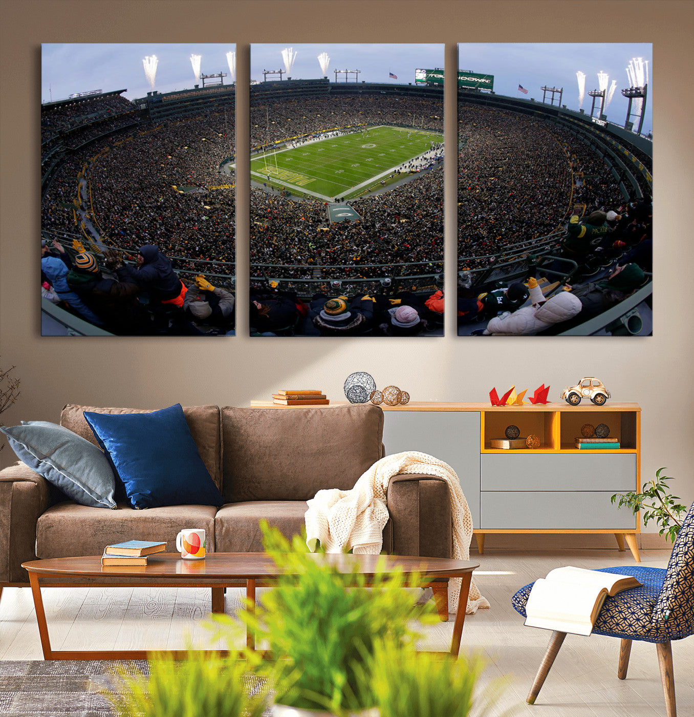 Wide fisheye view of a packed Lambeau Field stadium during an American football game. The crowd fills the stands, and fireworks are going off above the stadium lights. The scoreboard displays "Touchdown," and the field has "Packers" painted in the end zon