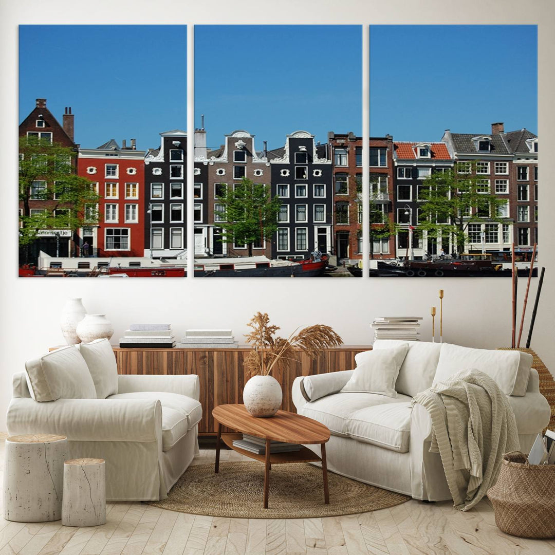 The Amsterdam City Wall Art Canvas Print showcases colorful traditional canal houses and boats set against a clear blue sky.