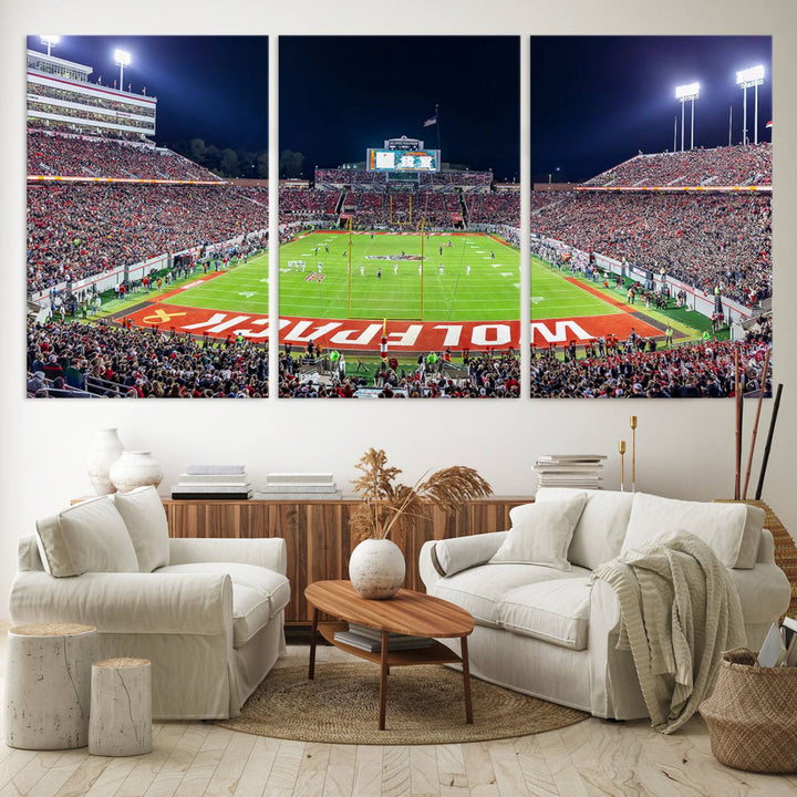 A NC State Wolfpack Football Team print of Carter-Finley Stadium at night features WOLFPACK illuminated brightly in the end zone grass.