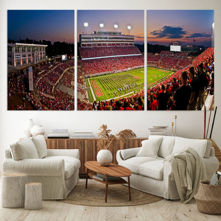 A print of a bustling Carter-Finley Stadium at dusk, featuring fans and a band, captures the essence of NC State Wolfpack football.