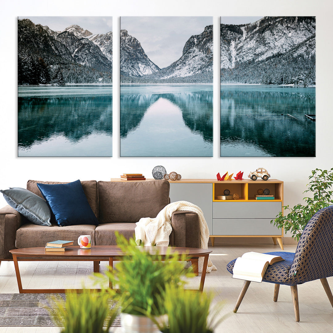 Crystal-clear alpine lake reflecting snow-covered mountains, surrounded by evergreen trees, creating a serene and tranquil winter landscape.