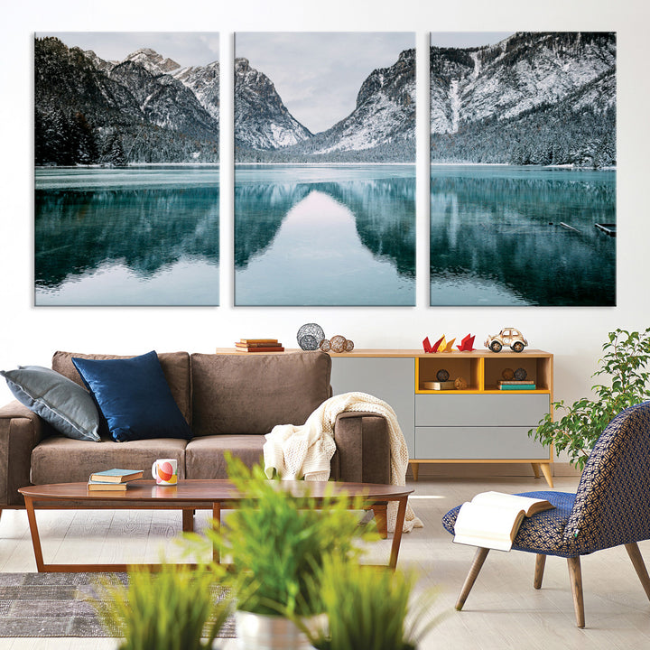 Crystal-clear alpine lake reflecting snow-covered mountains, surrounded by evergreen trees, creating a serene and tranquil winter landscape.