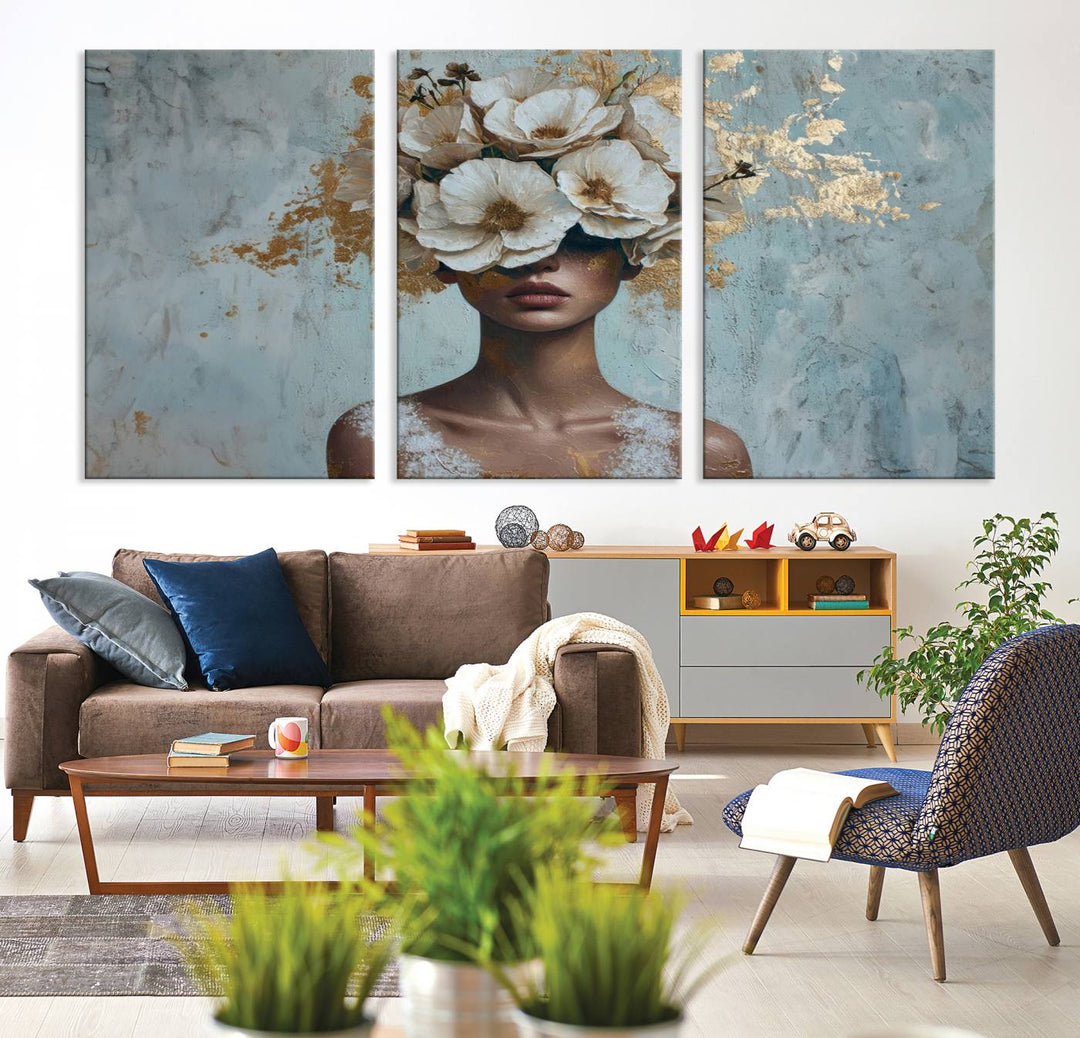 The Golden Petal Silhouette Woman Wall Art Canvas Print, a large 3-panel canvas with a textured gold floral design, serves as a luxurious centerpiece in modern glam settings. The artwork depicts a woman with flowers over her eyes against a textured background and hangs elegantly.