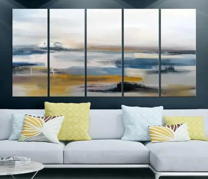 The Abstract Landscape Wall Art Canvas, featuring a 3-panel design in blue, gold, and white, seamlessly blends into the chic modern decor of the living room. This large abstract print enhances the space with its elegant presence.