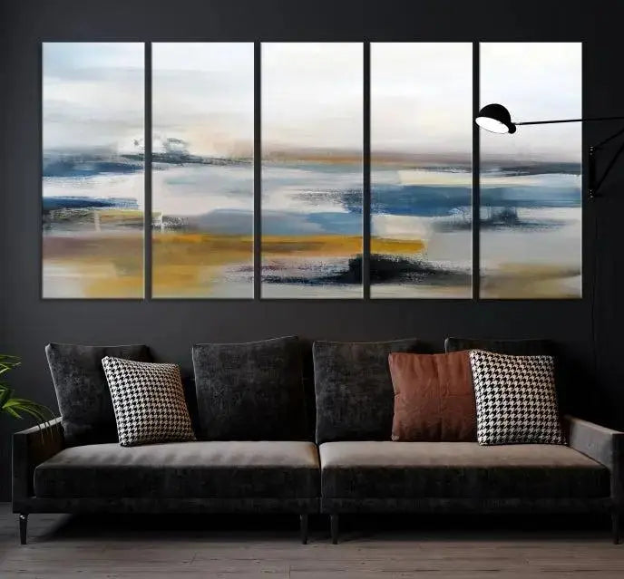 The Abstract Landscape Wall Art Canvas, featuring a 3-panel design in blue, gold, and white, seamlessly blends into the chic modern decor of the living room. This large abstract print enhances the space with its elegant presence.