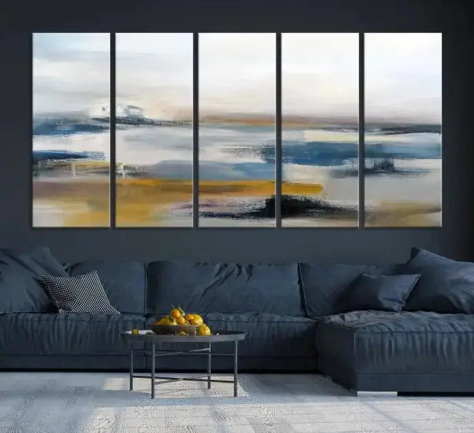 The Abstract Landscape Wall Art Canvas, featuring a 3-panel design in blue, gold, and white, seamlessly blends into the chic modern decor of the living room. This large abstract print enhances the space with its elegant presence.