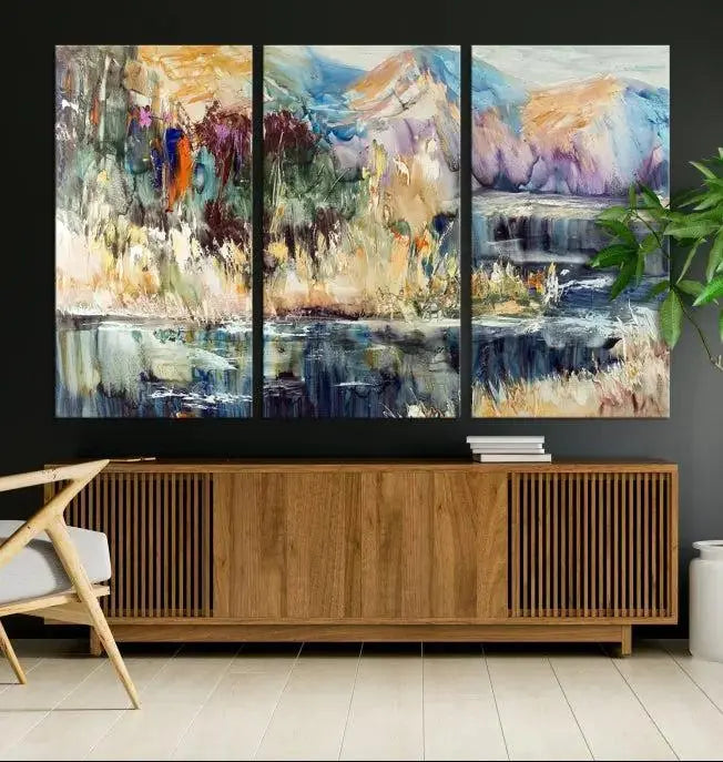 A vibrant Abstract Landscape Waterfall Canvas Art adorns the wall in this cozy living room. This 3-panel large wall art enhances the inviting space's vivid collection. This premium quality, ready-to-hang print is perfect for a living room, office, or lounge.