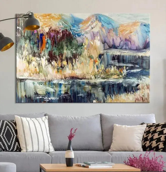 A vibrant Abstract Landscape Waterfall Canvas Art adorns the wall in this cozy living room. This 3-panel large wall art enhances the inviting space's vivid collection. This premium quality, ready-to-hang print is perfect for a living room, office, or lounge.