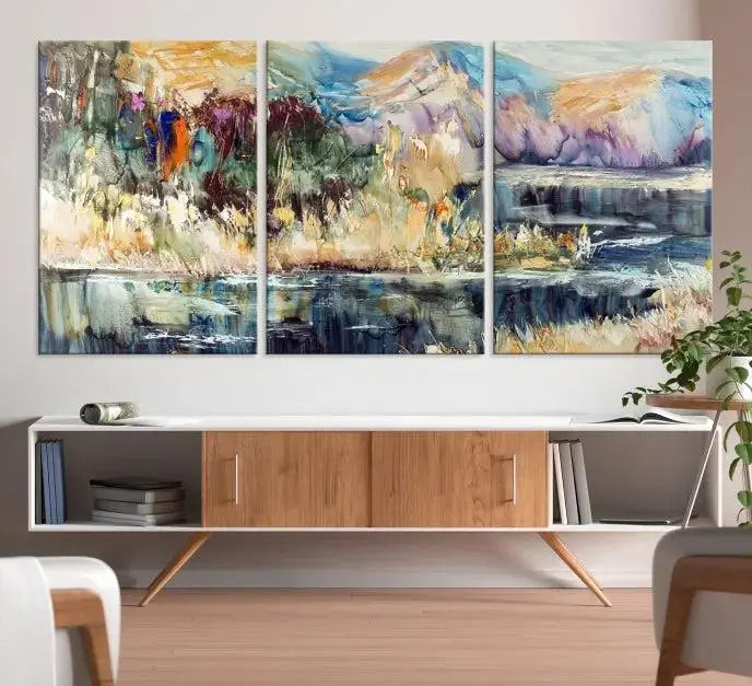 A vibrant Abstract Landscape Waterfall Canvas Art adorns the wall in this cozy living room. This 3-panel large wall art enhances the inviting space's vivid collection. This premium quality, ready-to-hang print is perfect for a living room, office, or lounge.