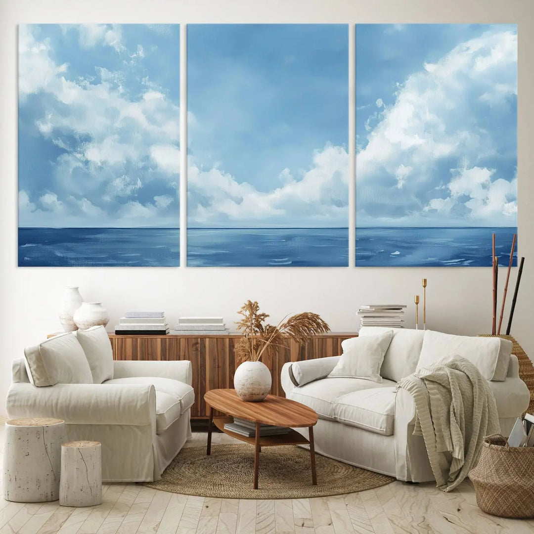 A modern living room with coastal decor features the "Serene Blue Ocean Canvas Wall Art" - a minimalist abstract ocean print. The large paintings add a serene touch to the space, enhancing the tranquil vibe.